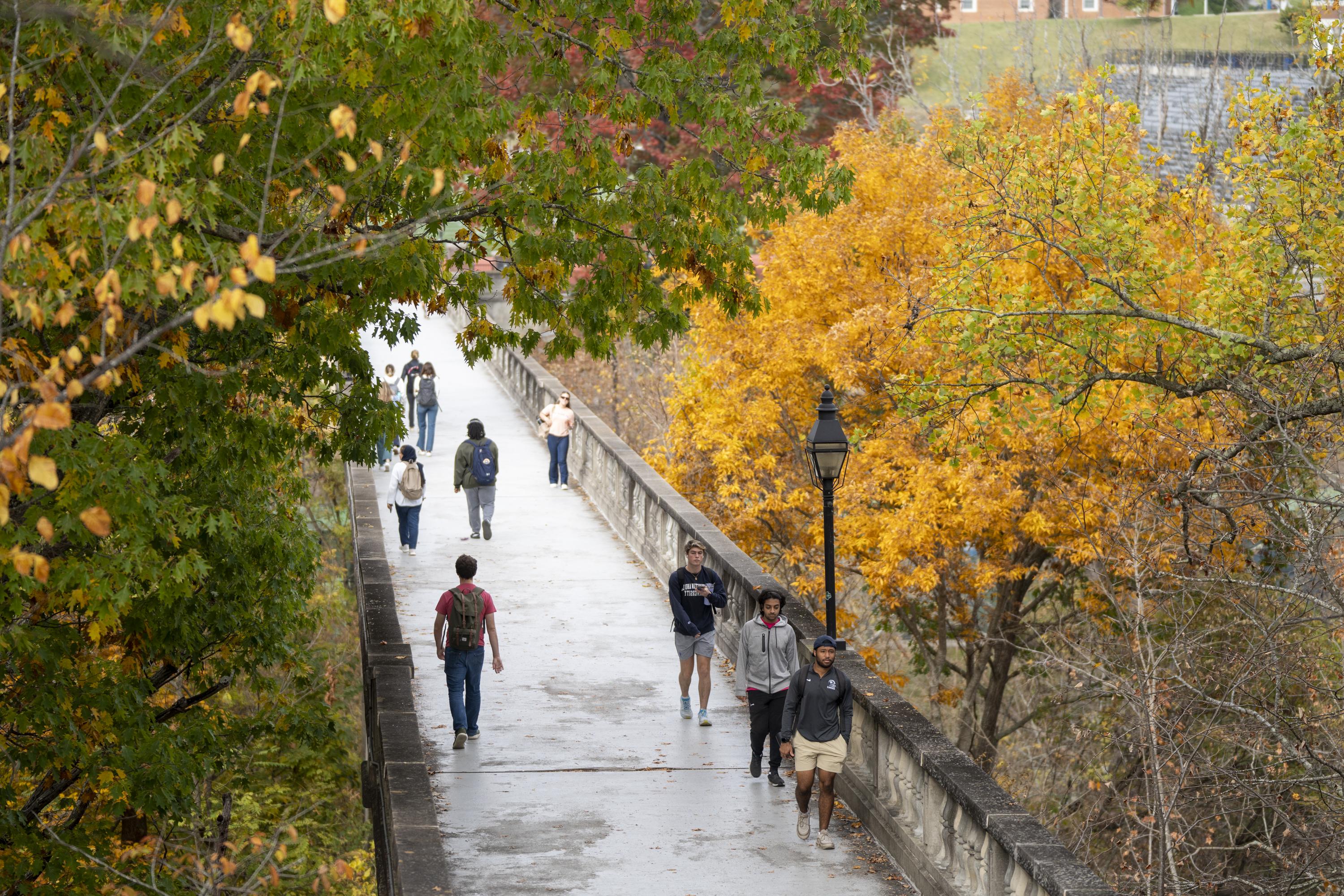 People cross Wilson Field Bridge in the fall