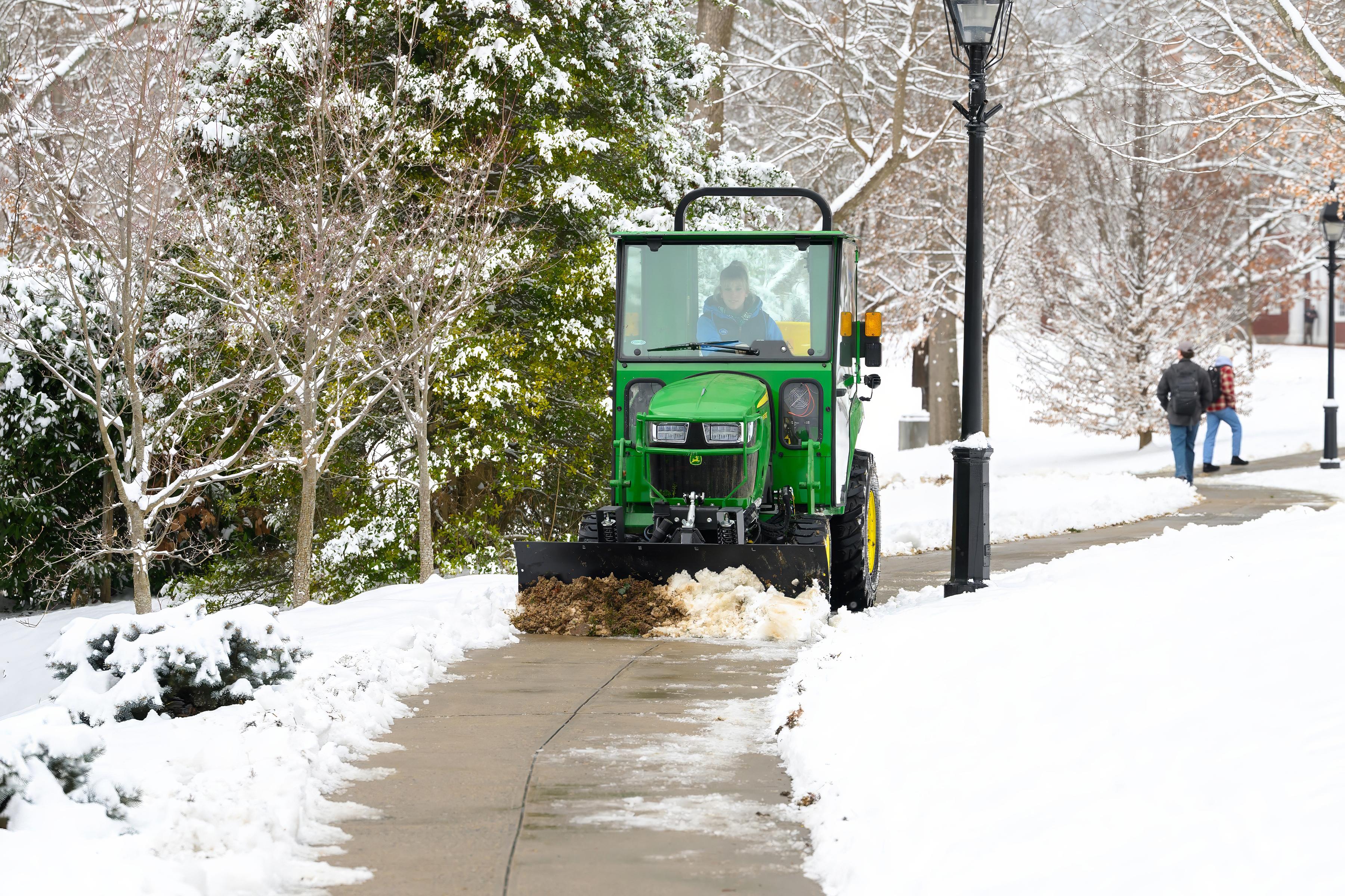 Grounds worker clears snow from campus walkways